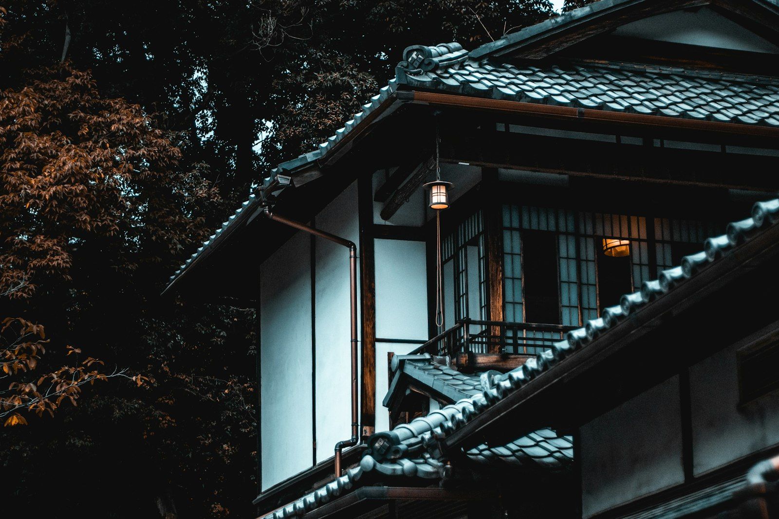 木々に囲まれた、瓦屋根と白壁の二階建ての家