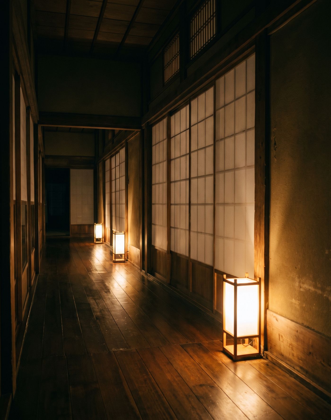 行灯が足もとを照らす、離れへ続く夜の板張りの廊下
