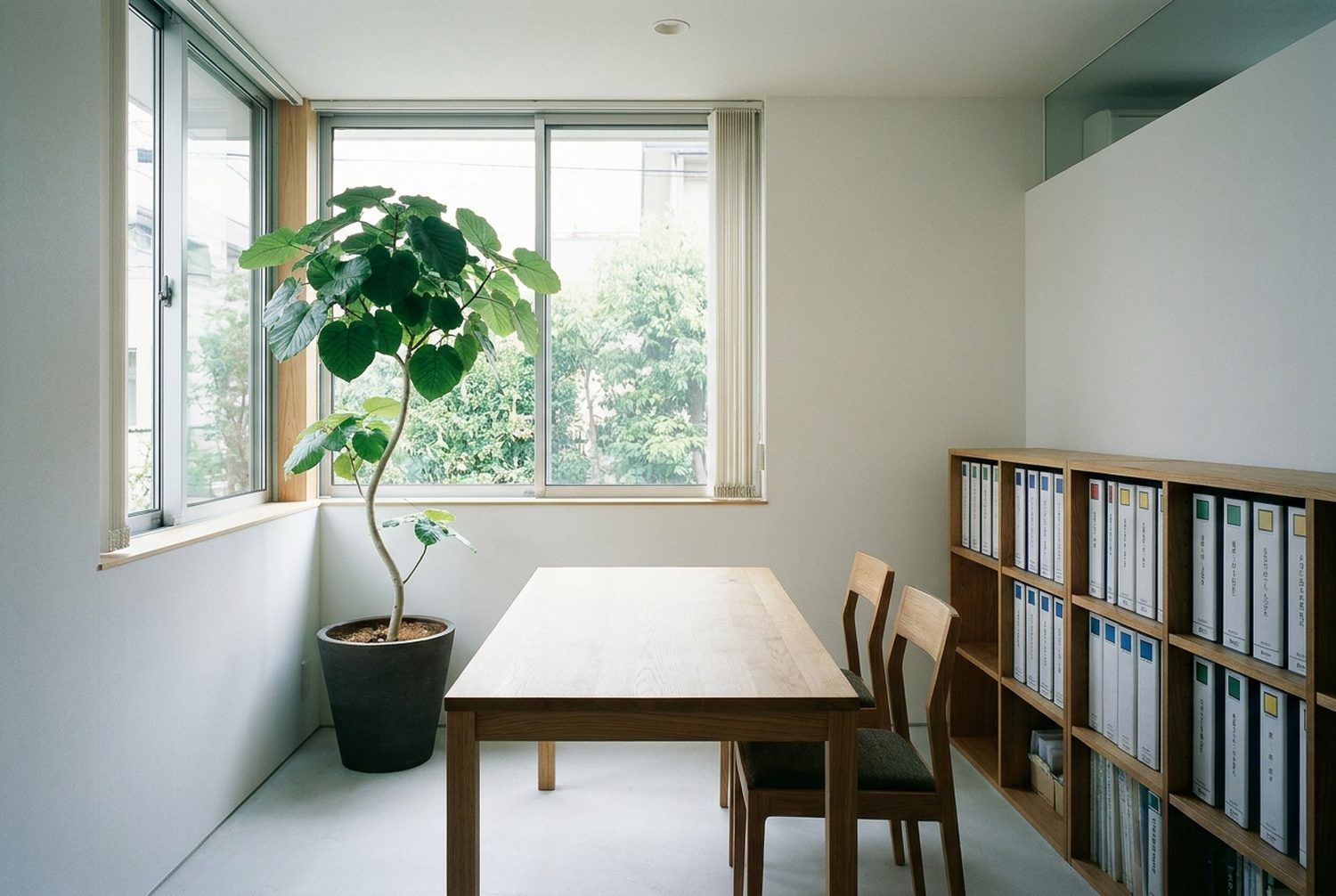 白い壁と木の机がある、明るい打ち合わせの部屋